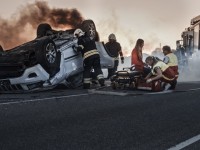 photo-of-a-car-accident-scene-with-vehicle-fliiped-over-and-woman-being-treated-by-paramedics.jpg